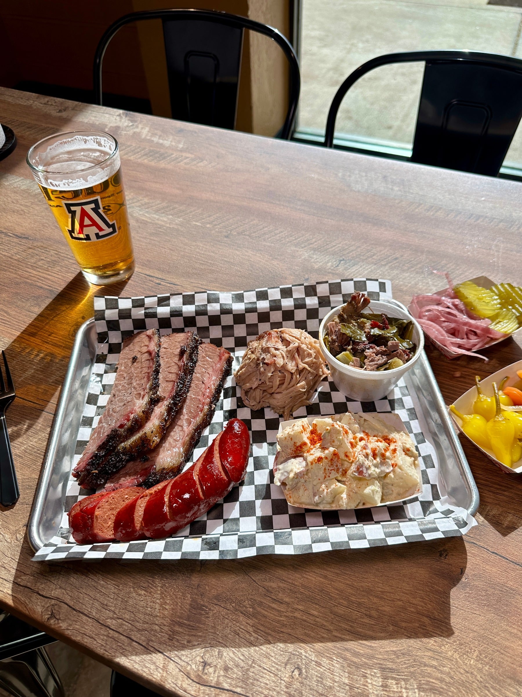 A tray of smoked BBQ with sides and a beer at BubbaQue